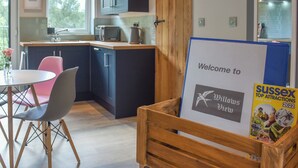 Une cuisine moderne avec des meubles de couleur sombre, une porte en bois, une pancarte de bienvenue et un plan des attractions du Sussex.