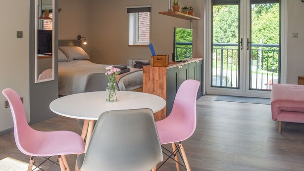 Une chambre moderne équipée d’un lit, d’une table à manger avec des chaises, d’une télévision et d’un balcon avec vue.