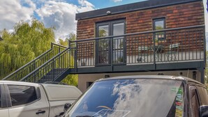 Un immeuble doté d’un balcon, d’un escalier et d’une voiture garée.