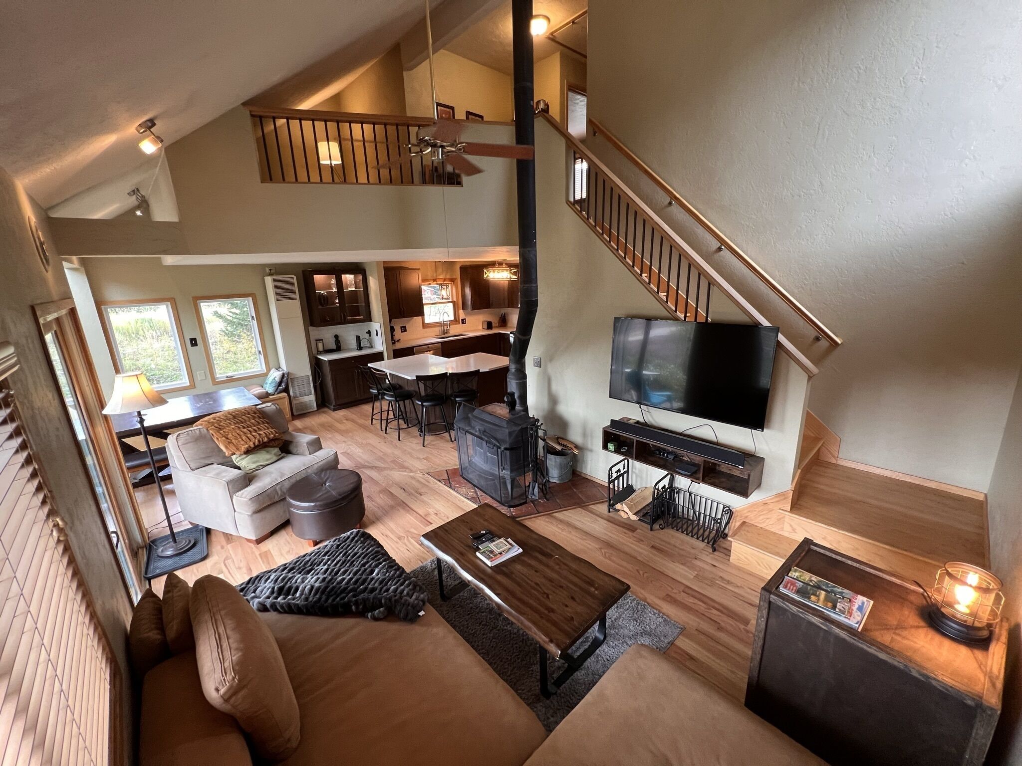 Un vaste espace de vie comprenant un grand canapé, une table basse, un téléviseur et un escalier menant à un niveau supérieur.