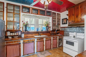 Una cocina con gabinetes de madera, una estufa blanca y un ventanal con flores.