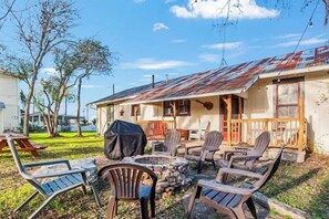 An outdoor seating area with a fire pit, chairs, and a covered grill. - Carriage Inn - Cottage (Bandera)