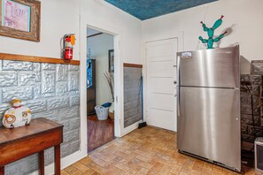 A kitchen with a refrigerator, a wooden table, and a wall with a textured design.