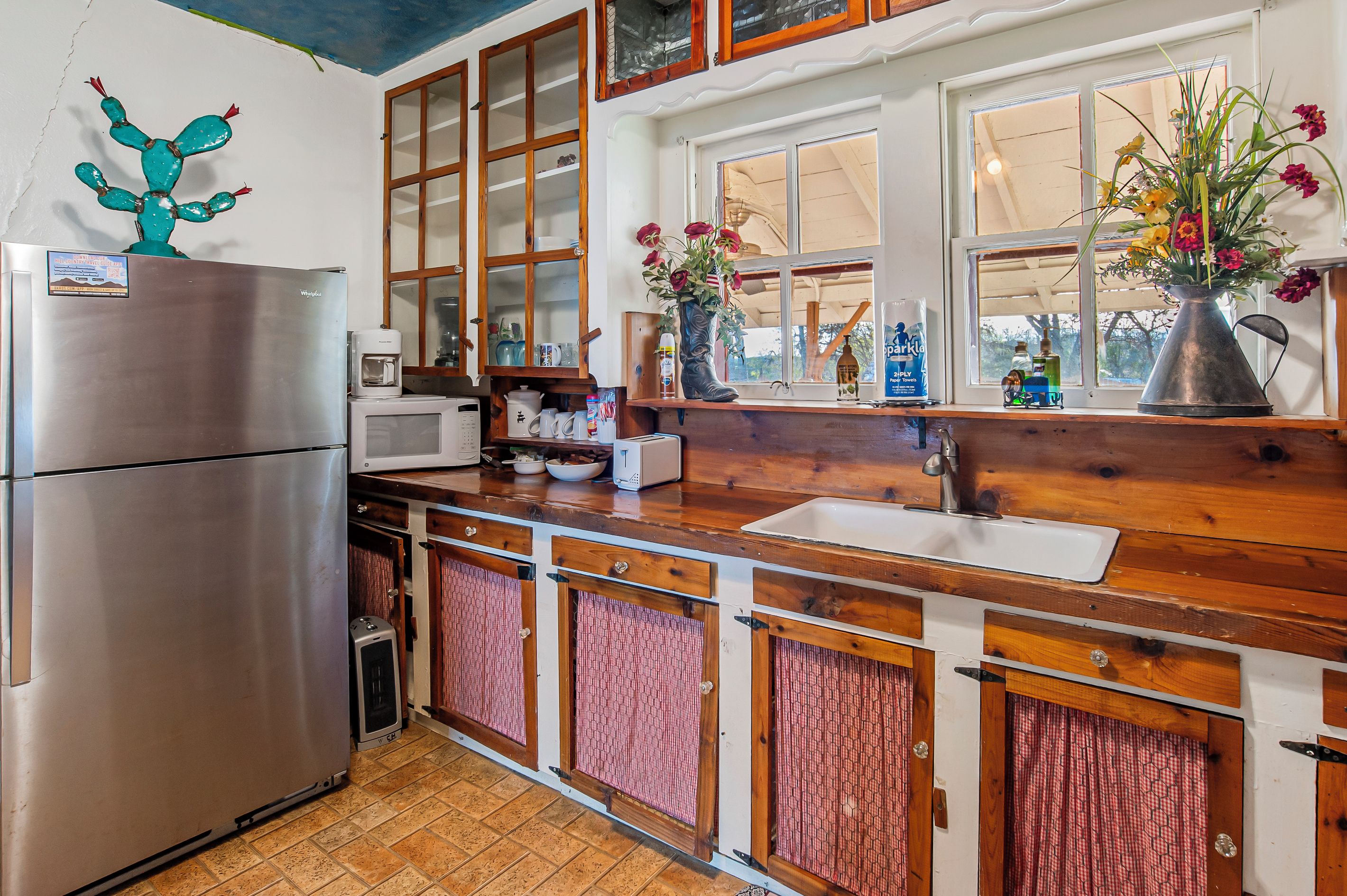 A kitchen with wooden cabinets, a stainless steel refrigerator, a microwave, and a sink.