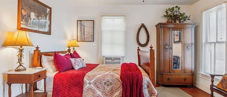 A bedroom with a bed, bedside lamps, a dresser, a mirror, and a window with blinds.