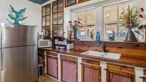 A kitchen with a stainless steel refrigerator, wooden cabinets, a microwave, and a sink. - Carriage Inn - Cottage (Bandera)