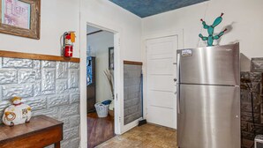 A kitchen with a stainless steel refrigerator, a wooden table with a decorative item, and a textured wall. - Carriage Inn - Cottage (Bandera)