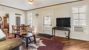 A living room with a dining area, a television, and a ceiling fan. - Carriage Inn - Cottage (Bandera)