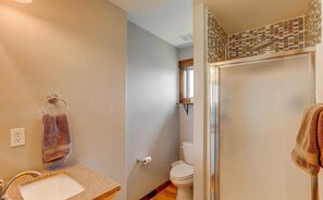 A bathroom with a sink, towel rack, toilet, and shower area.