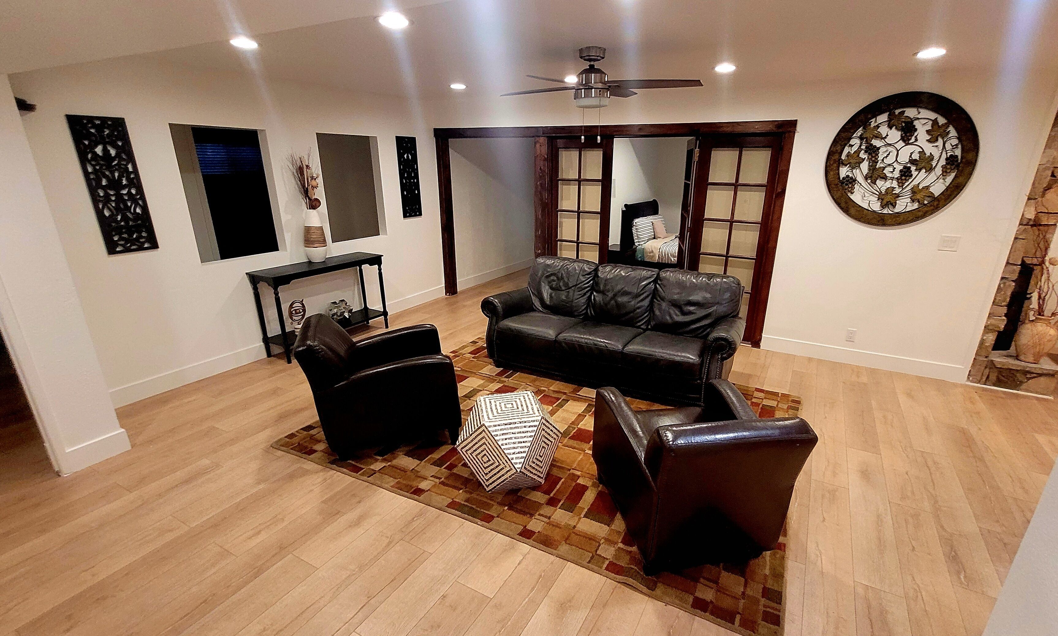A spacious living room with a black leather sofa, a matching armchair, and a coffee table.