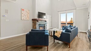 Amplia sala de estar con chimenea de piedra, un sofá grande y un candelabro.