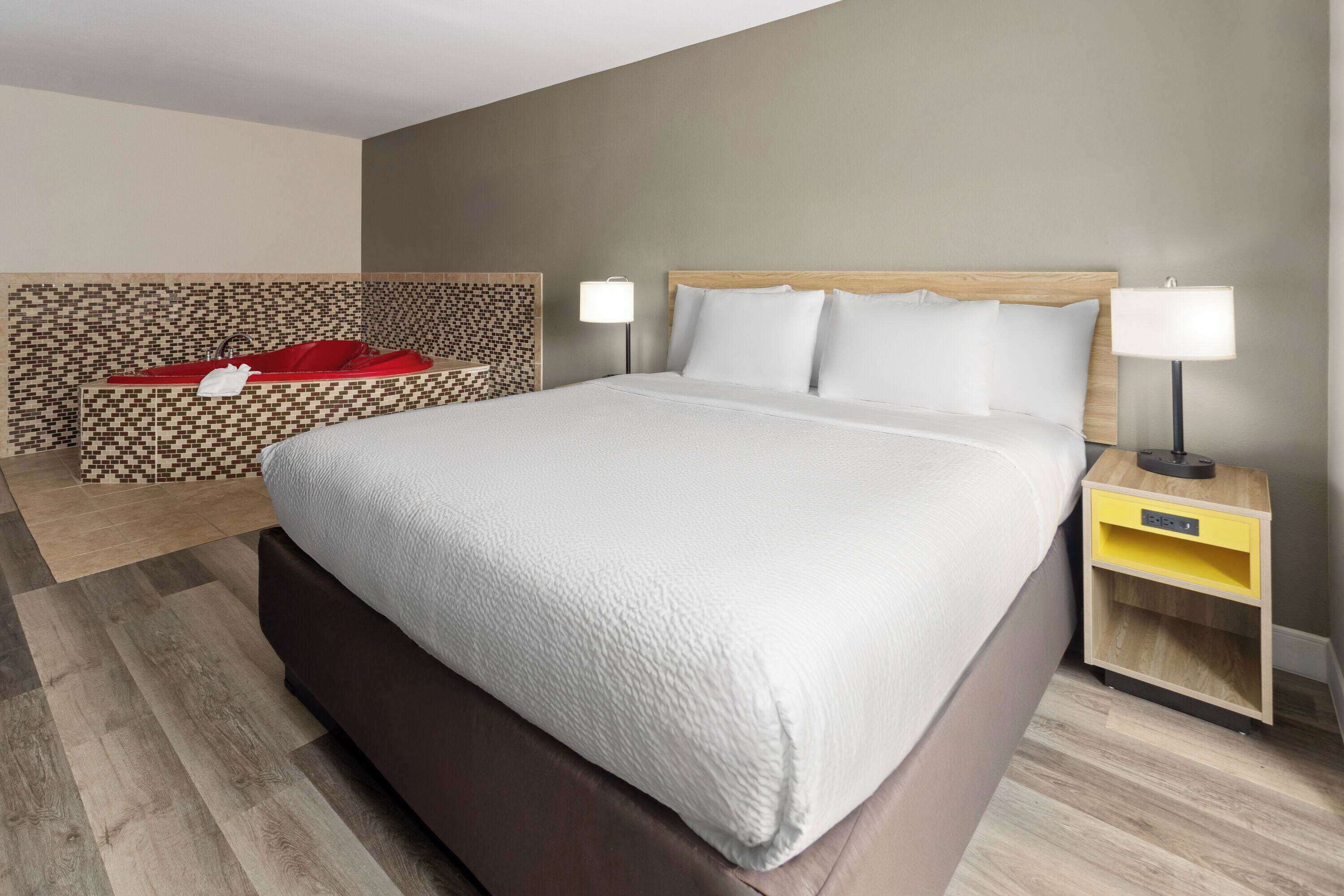 Een hotelkamer met een groot bed, twee nachtkastjes en een behang met een patroon.