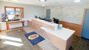 Un área de recepción con mostrador, computadora y televisor.