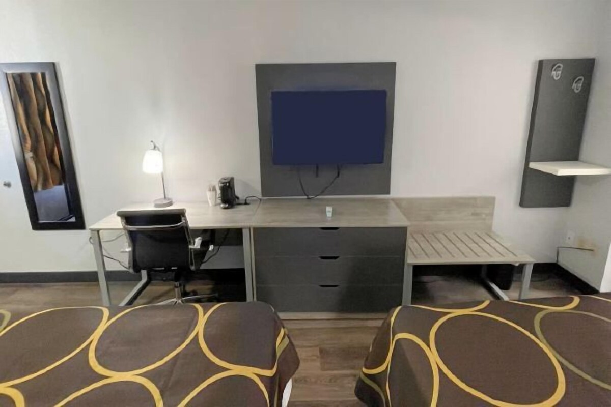 A hotel room with a desk, chair, and a bed with patterned bedding.