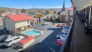 Un hotel con piscina, estacionamiento y vistas a un pueblo con una iglesia y una arcade.
