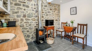 Una pared de piedra, una chimenea, un televisor y muebles de madera en una habitación.