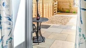 Un patio con una mesa, sillas, una botella de vino y una valla de madera.