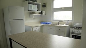 A compact kitchen with white appliances, a countertop, and a window.