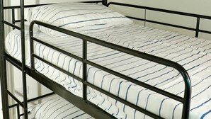 A bunk bed with three levels, each with a white mattress featuring blue stripes.