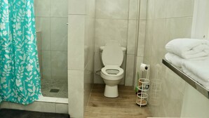 A bathroom with a toilet, a shower, and a towel rack.