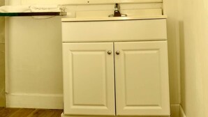 A bathroom with a white vanity, a mirror, and a light fixture above the mirror.