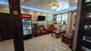 A hotel lobby with a Coca-Cola refrigerator, wooden furniture, and potted plants. - HOTEL VISTA MAR (Puerto Montt)
