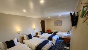 A hotel room with three beds, a flat-screen TV, a painting on the wall, and a patterned carpet. - HOTEL VISTA MAR (Puerto Montt)