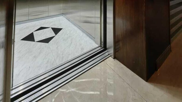 An elevator interior with reflective walls, a geometric floor pattern, and a control panel on the right. - HOTEL VISTA MAR (Puerto Montt)