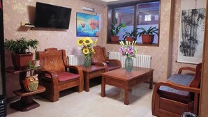 A living room with wooden furniture, a flat-screen TV, a painting, and potted plants. - HOTEL VISTA MAR (Puerto Montt)