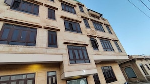 A multi-story building with a beige facade, multiple windows, and a closed shutter on the ground floor. - Hotel Urban Heritage (Jaisalmer)