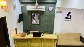 A reception area with a reception desk, a clock, a framed picture, and a sofa. - Hotel Urban Heritage (Jaisalmer)
