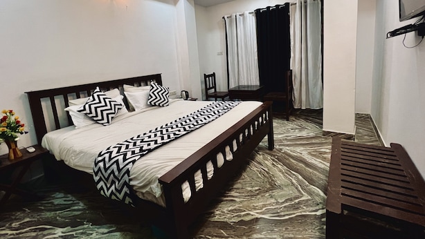 A bedroom with a bed, bedside table, and a small table with chairs. - Hotel Urban Heritage (Jaisalmer)