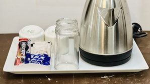 A stainless steel electric kettle, a glass jar, a white plate, and a Nestle coffee sachet on a white tray. - Hotel Urban Heritage (Jaisalmer)