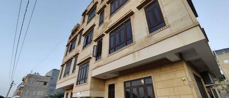 A multi-story building with a beige facade, multiple windows, and a visible entrance.