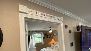 A room with a bed, a TV, and a sign reading "EUROPEAN ROOM". - Fish Camp - Backyard Caney Creek Fishing -  7.5 Miles from the Gulf (Bay City)
