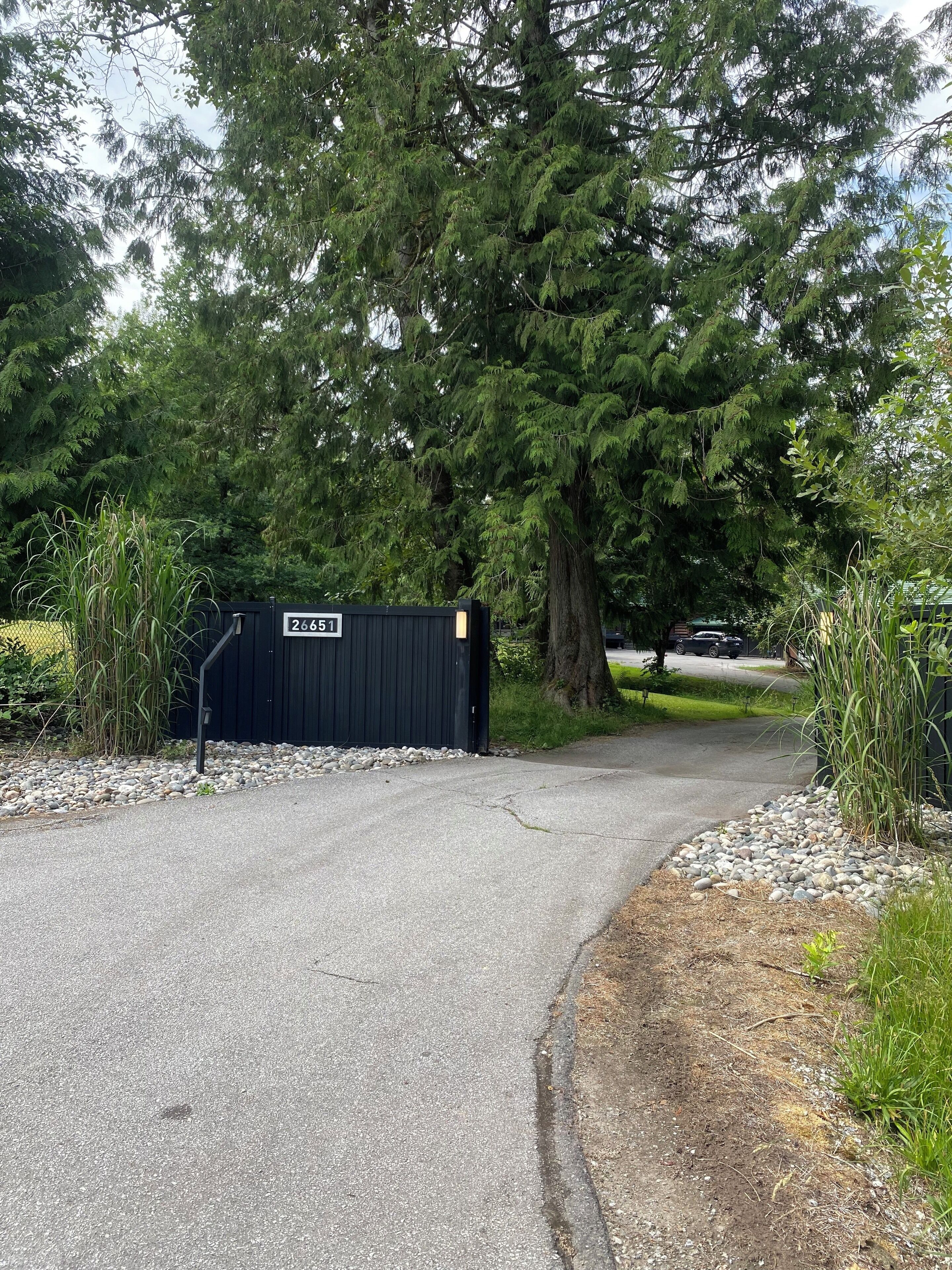 A gated driveway leading to a building with a sign reading "26651".