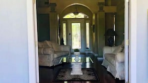 Un salon spacieux avec une table basse en verre, deux canapés blancs et un tapis décoratif.
