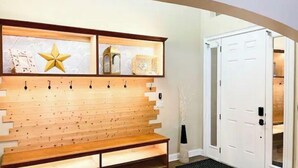 A reception area with a wooden bench, a wall-mounted coat rack, and a white door.