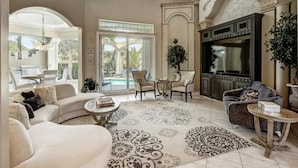 A spacious living room with a large window, a fireplace, and a pool view. - Private heated pool, Luxury Mediterranean Mansion sleeps 16 (Destin)