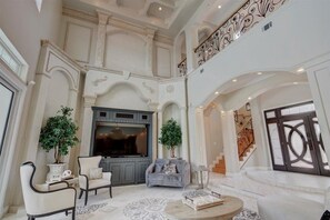 Amplia sala de estar con un mueble de entretenimiento grande, asientos cómodos y una escalera que conduce a un nivel superior.