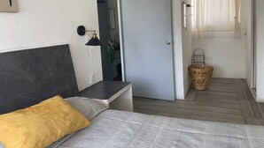 A bedroom with a bed, a bedside table, a lamp, a wardrobe, and a door leading to a bathroom. - Apartment with pool 10 minutes from Playa Chahue (Crucecita)
