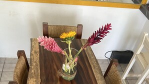A wooden dining table with a glass vase containing flowers. - Apartment with pool 10 minutes from Playa Chahue (Crucecita)