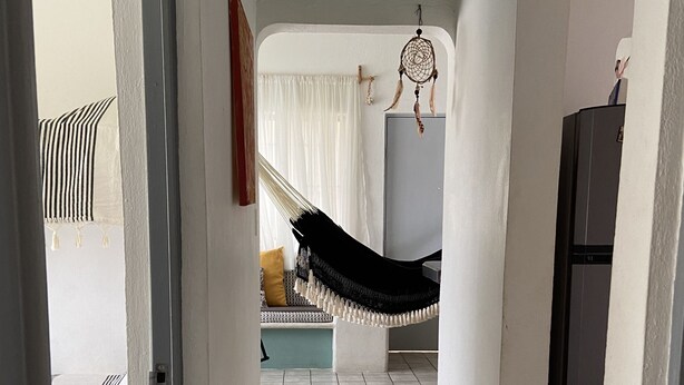 A hallway with a hammock, a sofa, and a refrigerator. - Apartment with pool 10 minutes from Playa Chahue (Crucecita)