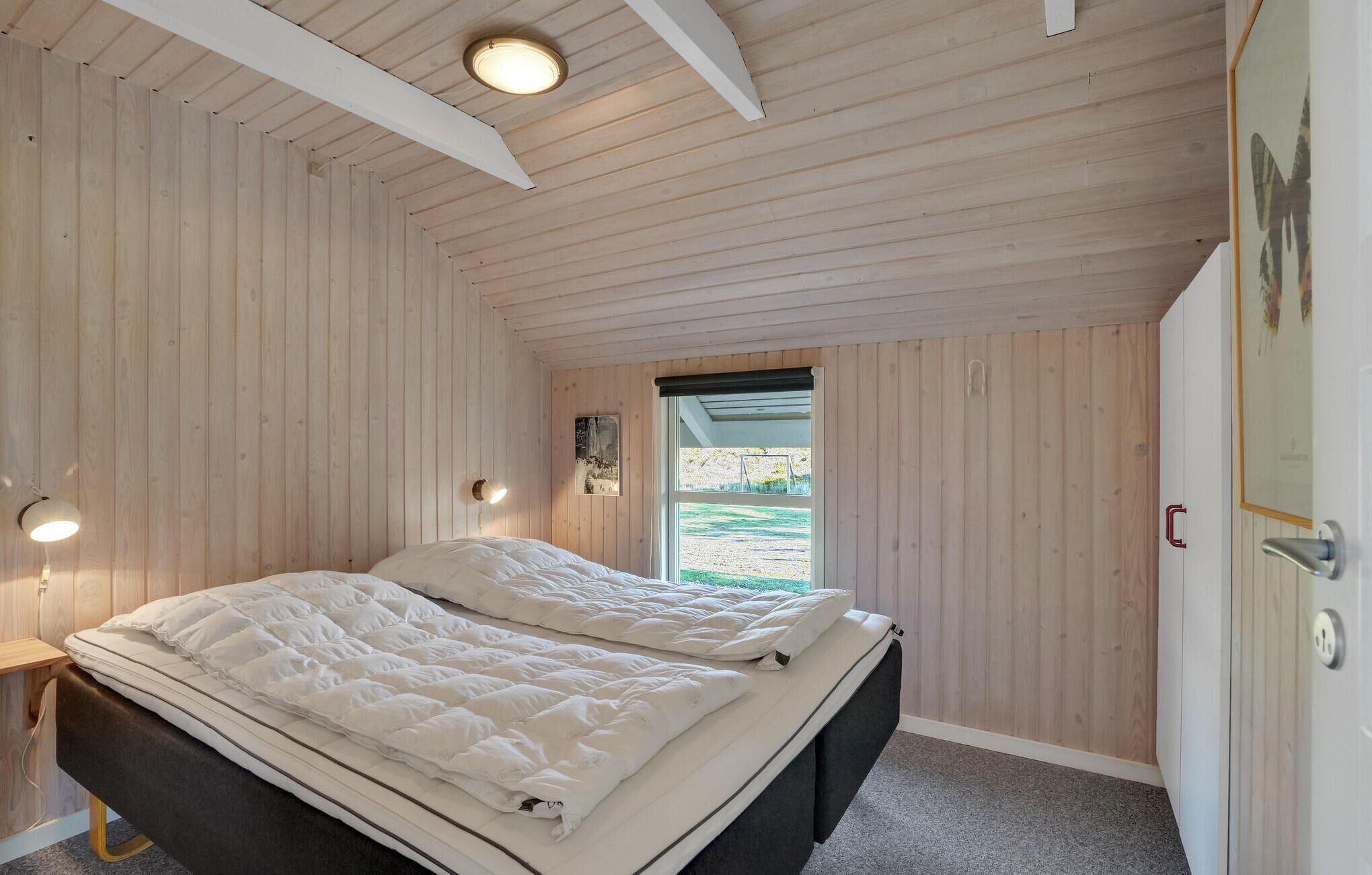 Een slaapkamer met twee bedden, houten wanden, een raam met uitzicht en een deur met slot.