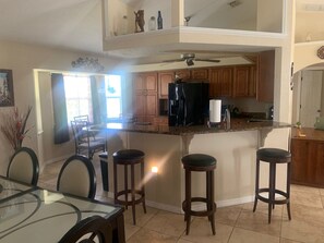 A spacious kitchen with a central island, wooden cabinets, and a black refrigerator. - Serene 3BR Retreat with 2 Baths - Your Perfect Getaway Awaits! (Port Charlotte)