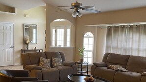 Ein geräumiges Wohnzimmer mit zwei Sofas, einem Couchtisch und einem Deckenventilator.