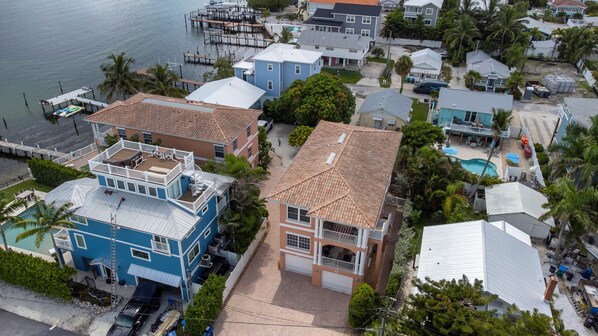 A coastal residential area with houses featuring balconies and a swimming pool. - Top Floor Condo with Heated Pool located steps from Gulf of Mexico and Tampa Bay (Bradenton Beach)