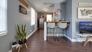 A modern kitchen with a bar area, a refrigerator, and a television on a stand. - Medical District Gem (Memphis)