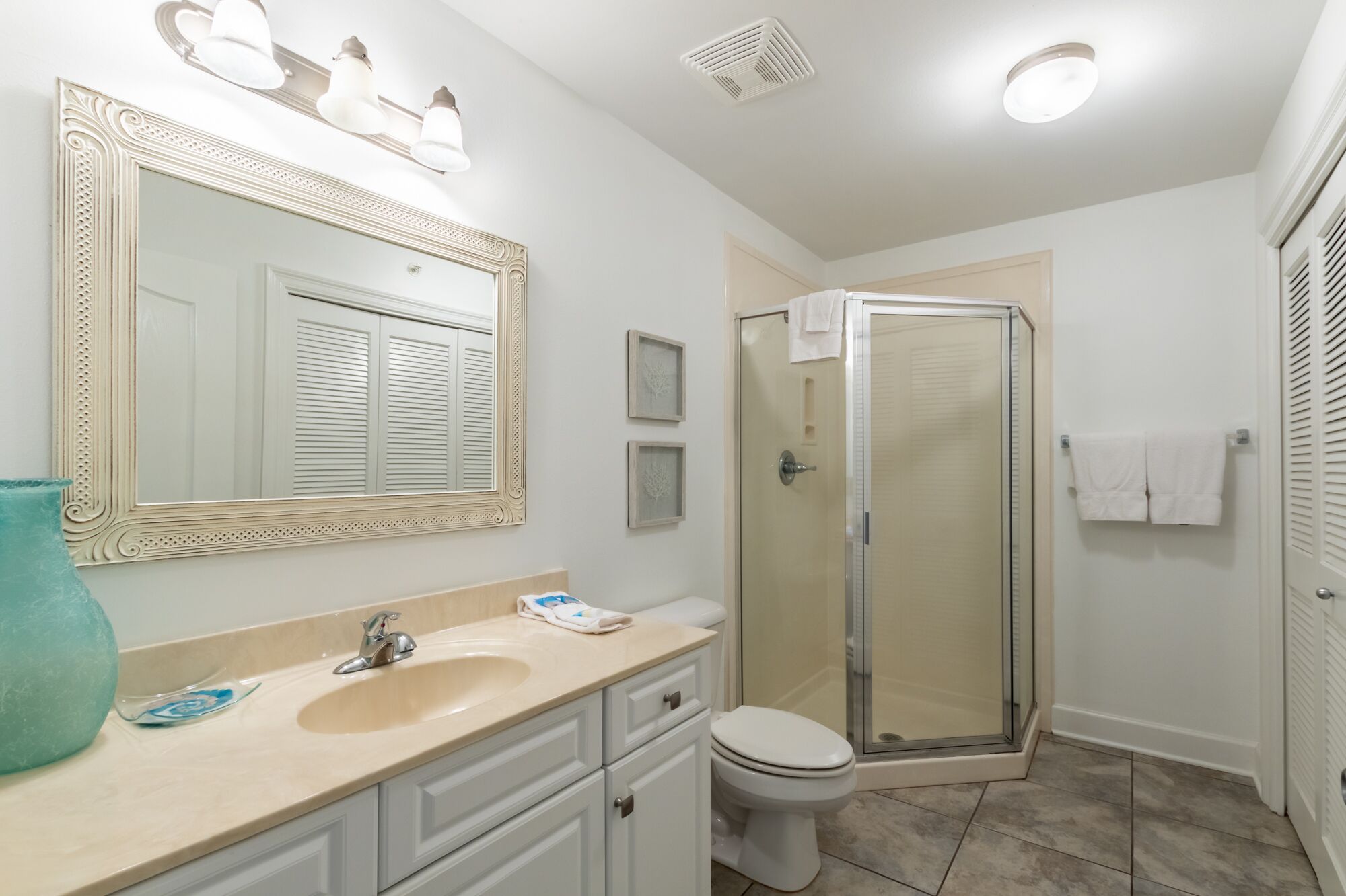 A bathroom with a sink, mirror, toilet, and shower.