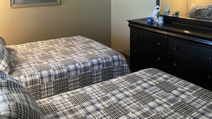 Une chambre avec deux lits, un ventilateur de plafond, une commode et un tableau au mur.